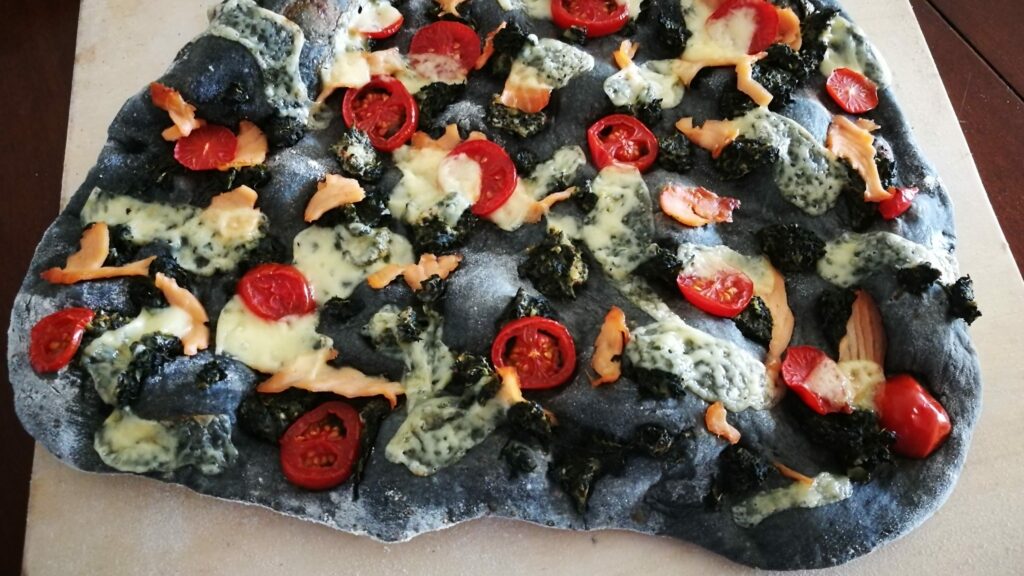 schwarze Pizza mit Tomaten