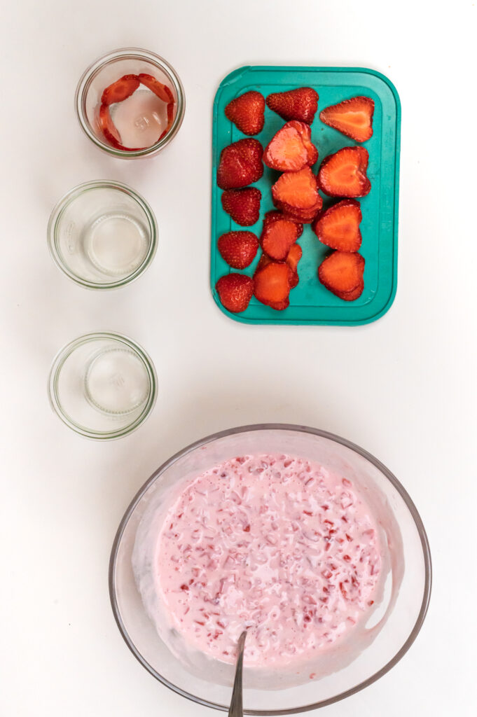 Für das Erdbeerquark - Dessert die Erdbeerscheiben in das Glas setzen
