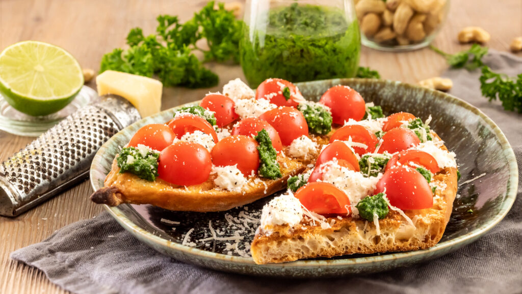 Tomaten, Ricotta und selbst gemachtes Petersilien-Pesto auf gegrillten Brotscheiben.
